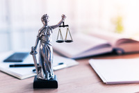 Eine Figur der Justitia steht auf einem Schreibtisch