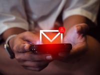 Zwei Hände halten ein Smartphone, über dem ein Mail-Symbol mit Warnhinweis schwebt