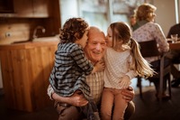 Ein Großvater der von seinen Enkelkindern einen Kuss bekommt. Das Bild zeigt einen Großvater, der von seinen Enkelkindern einen Kuss bekommt.